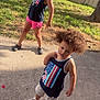 child, children, outdoor, grass, sidewalk, fence, tree, curly_hair, shorts, tank_top, sneakers, crocs, smiling, posing, summer, daylight, playful, person, casual_clothing, nature