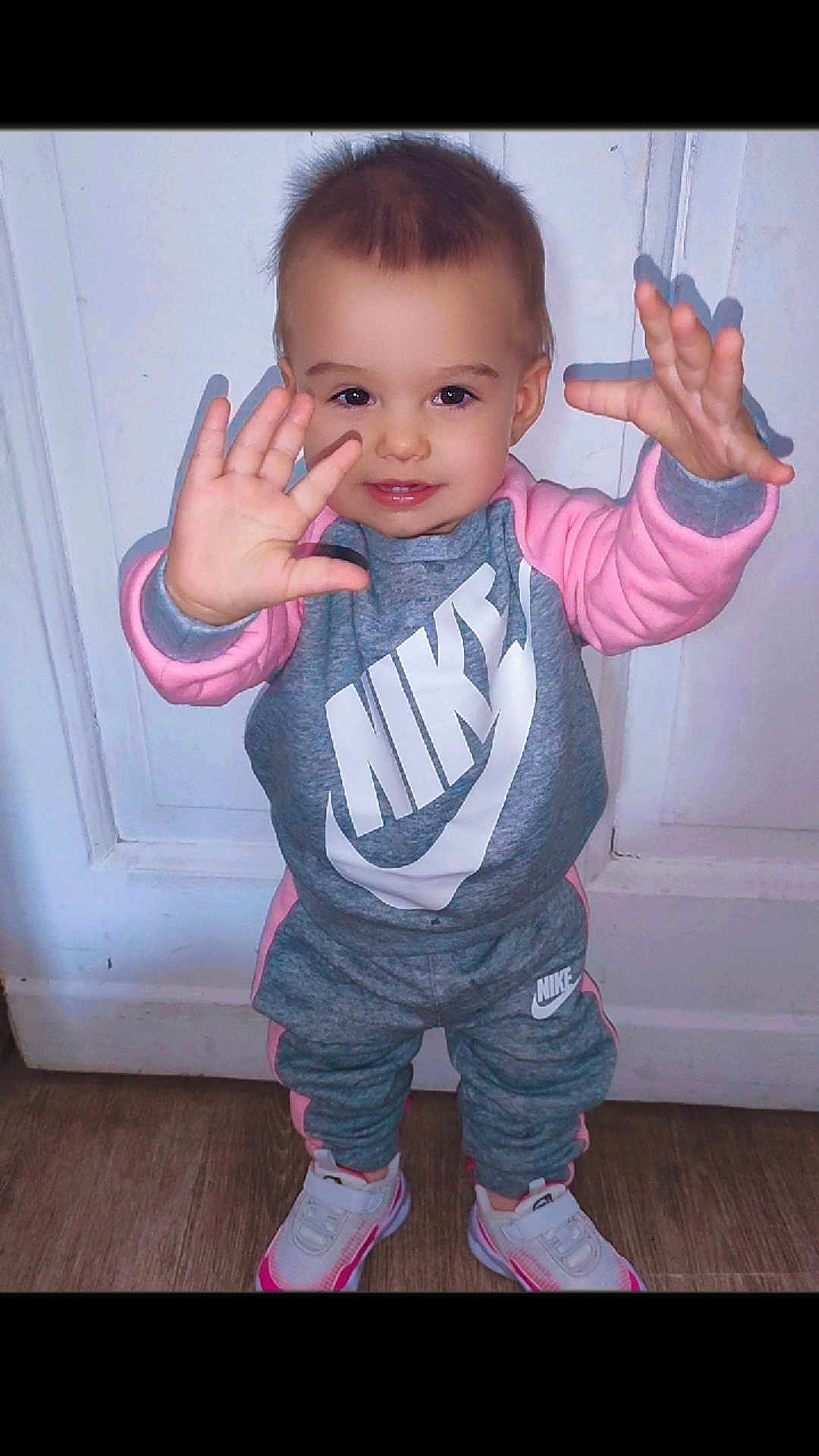 Jade a rejoint le concours — aidez-le/la à gagner de superbes lots ! toddler, child, nike, tracksuit, sneakers, indoor, wooden_floor, white_door, smiling, hands_up, playful, casual_clothing, young_child, sporty, cute, portrait, full_body, standing, fashion, happy