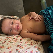Makari joined the competition — help win amazing prizes! baby, smiling, face, hand, blanket, pillow, floral_pattern, knitted_blanket, infant, cute, lying_down, happy, indoors, skin, head, expression, comfort, cozy, child, portrait