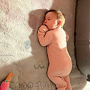 Zanica is registered to the contest to win money with this photo: baby, sleeping, onesie, blanket, shadow, doll, hand, soft_texture, infant, cozy, child, peaceful, indoors, cute, portrait, resting, pink_clothing, floor, toy, room