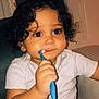 toddler, child, baby, curly_hair, toothbrush, white_clothing, indoor, portrait, cute, exploring, sitting, chubby_cheeks, big_eyes, hand, person, infant, brushing_teeth, young_child, face, light