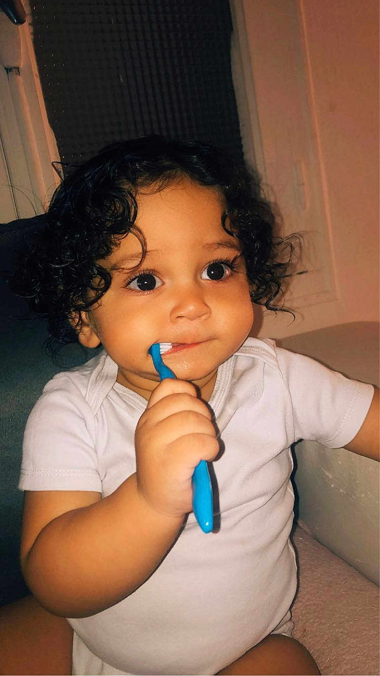 Abraham a rejoint le concours — aidez-le/la à gagner de superbes lots ! toddler, child, baby, curly_hair, toothbrush, white_clothing, indoor, portrait, cute, exploring, sitting, chubby_cheeks, big_eyes, hand, person, infant, brushing_teeth, young_child, face, light