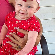 Braelyn Mae joined the competition — help win amazing prizes! adult, arms, baby, being_held, bow, chair, child, fashion, happy, headband, infant, outdoor, polka_dots, porch, portrait, red_outfit, sitting, smiling, sparkly, wooden_wall