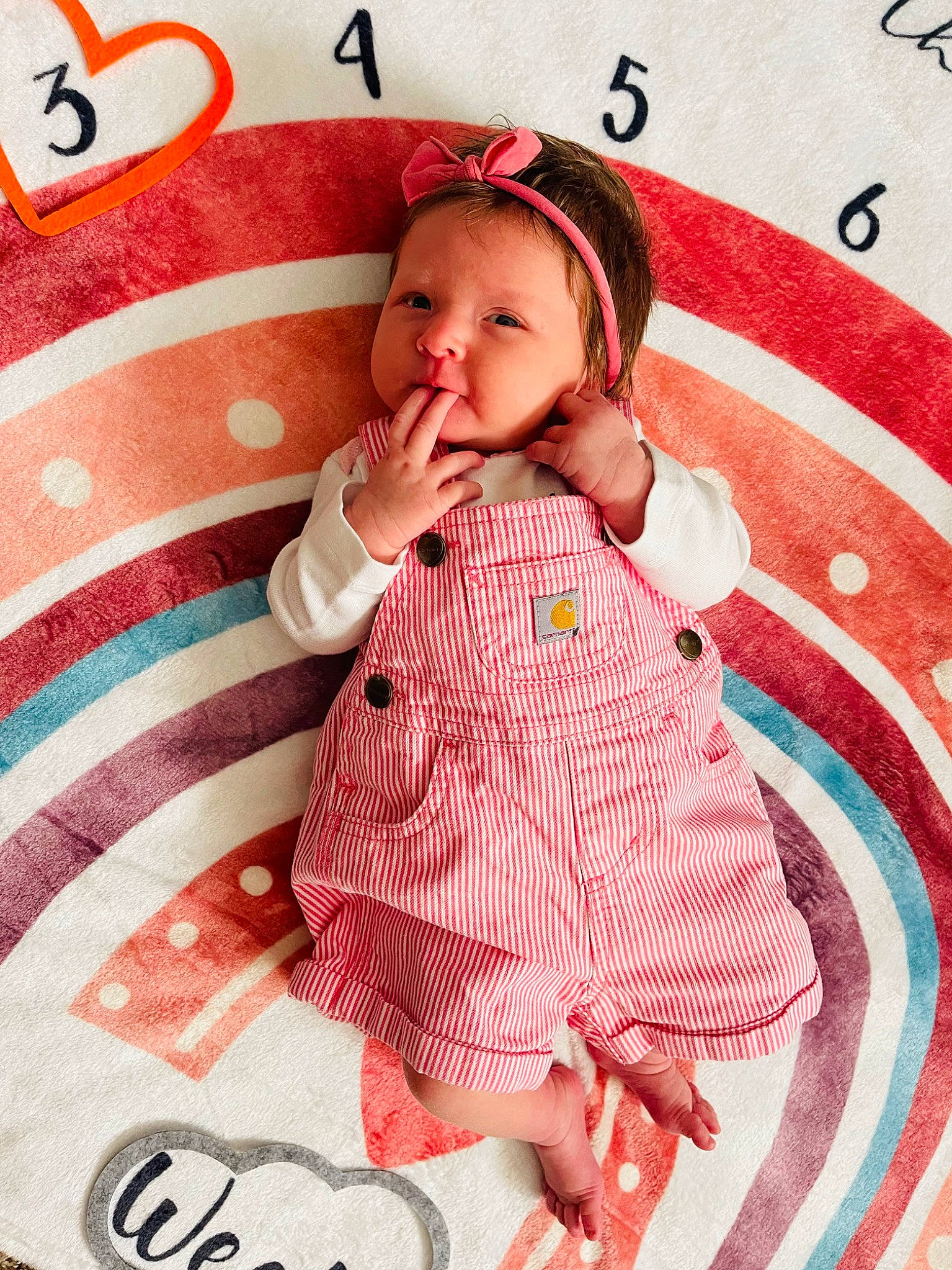 Hadley is registered to the contest to win money with this photo: baby, baby_products, baby_toddler_clothing, bedding, child, dress, face, fashion_accessory, happy, linens, magenta, outerwear, pattern, peach, person, pink, product, skin, sleeve, textile