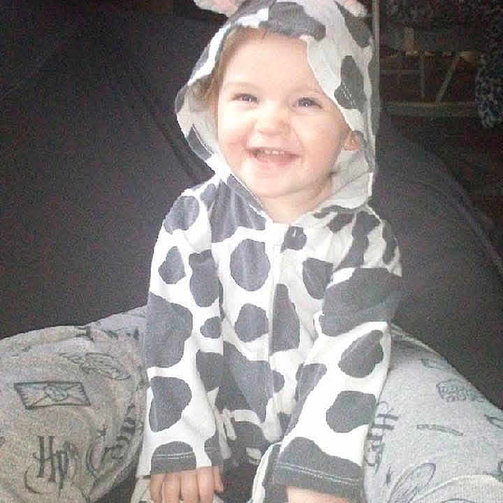 Kami joined the competition — help win amazing prizes! baby, child, clothing, cow_costume, cozy, cute, ears, fun, happy, hood, horns, indoor, joyful, legs, onesie, person, playful, sitting, smiling, toddler