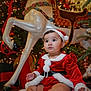 Madisson is registered to the contest to win money with this photo: baby, child, christmas, holiday, santa_outfit, red_clothing, white_fur_trim, hat, boots, blanket, carousel_horse, decorations, lights, festive, indoors, cute, portrait, seasonal, holiday_decor, christmas_tree