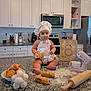baby, child, chef_hat, apron, kitchen, countertop, pastry, croissants, eggs, rolling_pin, mixer, flour, wooden_board, oven, microwave, cabinet, baking, cute, indoors, portrait