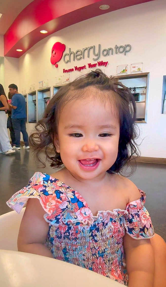 Crystal Hamamura is registered to the contest to win money with this photo: toddler, child, smiling, curly_hair, floral_dress, frozen_yogurt_shop, indoor, happy, person, baby, cute, portrait, fashion, seat, food_place, casual, bright, modern, people, background