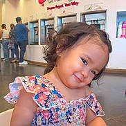 Crystal Hamamura joined the competition — help win amazing prizes! child, girl, curly_hair, smile, floral_dress, frozen_yogurt_shop, indoor, cute, person, young_child, seated, playful, happy, portrait, colorful, casual_clothing, head_tilt, people, background, food_shop
