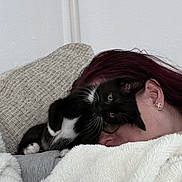 Isabella is registered to the contest to win money with this photo: cat, kitten, person, couch, blanket, indoor, cozy, snuggling, black_and_white, fur, earrings, hair, relaxing, cute, pet, resting, face, home, soft, comfort