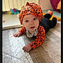 Léonie a rejoint le concours — aidez-le/la à gagner de superbes lots ! baby, child, infant, halloween, orange, headwrap, costume, floor, indoor, curious, lying_down, blue_eyes, clothing, patterned, cute, person, portrait, toddler, hand, soft_focus