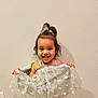child, girl, smile, dress, butterfly, hair, topknot, happy, standing, wall, indoor, power_outlet, pastel_colors, fabric, cute, young_child, portrait, holding, playful, fashion