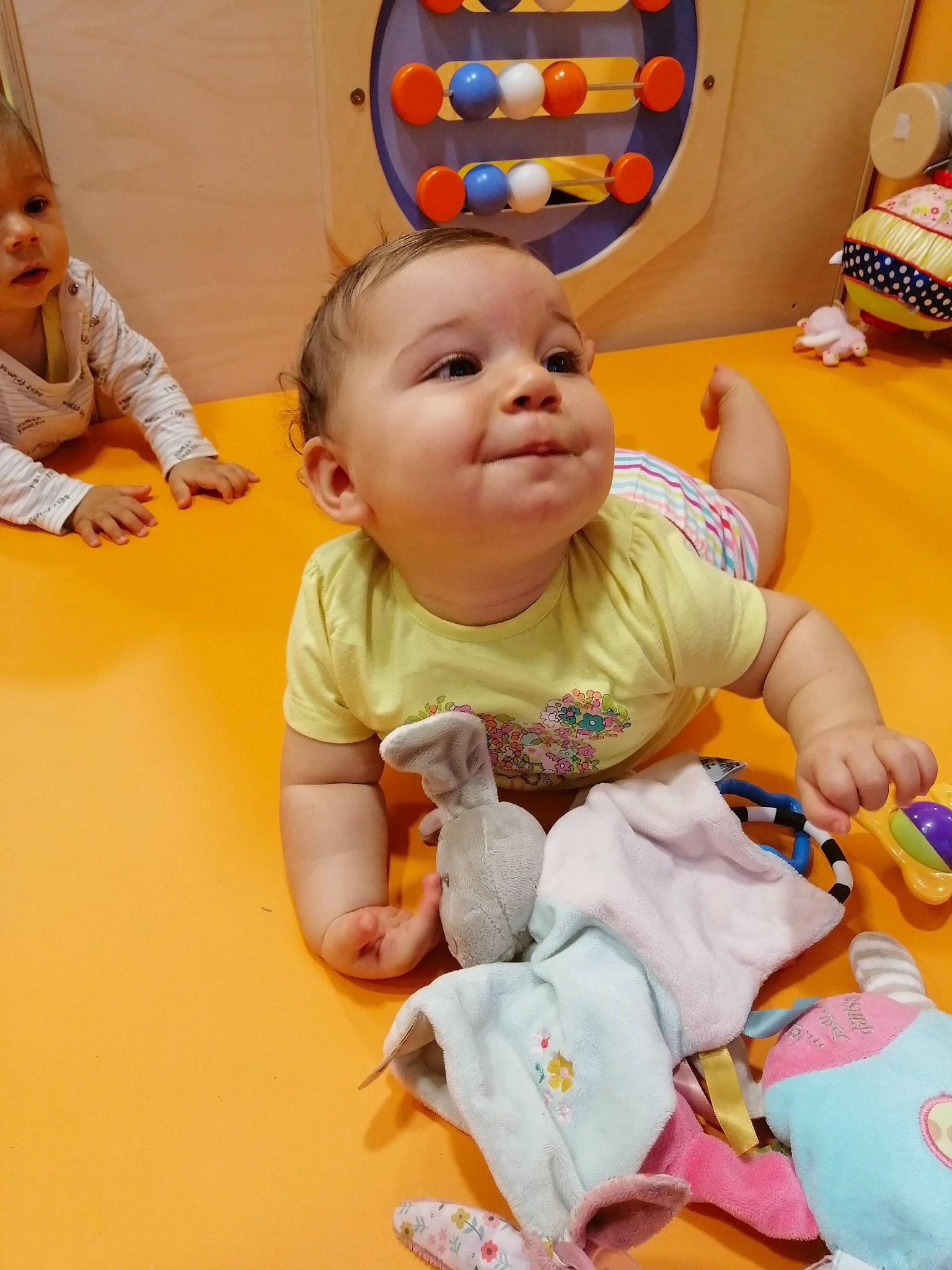 Luna a rejoint le concours — aidez-le/la à gagner de superbes lots ! baby, baby_toddler_clothing, cheek, child, event, face, facial_expression, flooring, fun, happy, head, leisure, orange, person, play, product, sitting, skin, smile, toddler