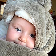 Jade a rejoint le concours — aidez-le/la à gagner de superbes lots ! baby, child, face, fur, hood, blue_eyes, cute, portrait, indoor, soft_texture, warm_lighting, teddy_bear_outfit, close_up, infant, adorable, person, cozy, snug, young, expression