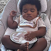 Kj joined the competition — help win amazing prizes! baby, sleeping, infant, afro_hair, bib, baby_seat, cushion, soft_toy, clothing, peaceful, indoor, carpet, relaxed, child, portrait, hands, feet, cute, resting, young