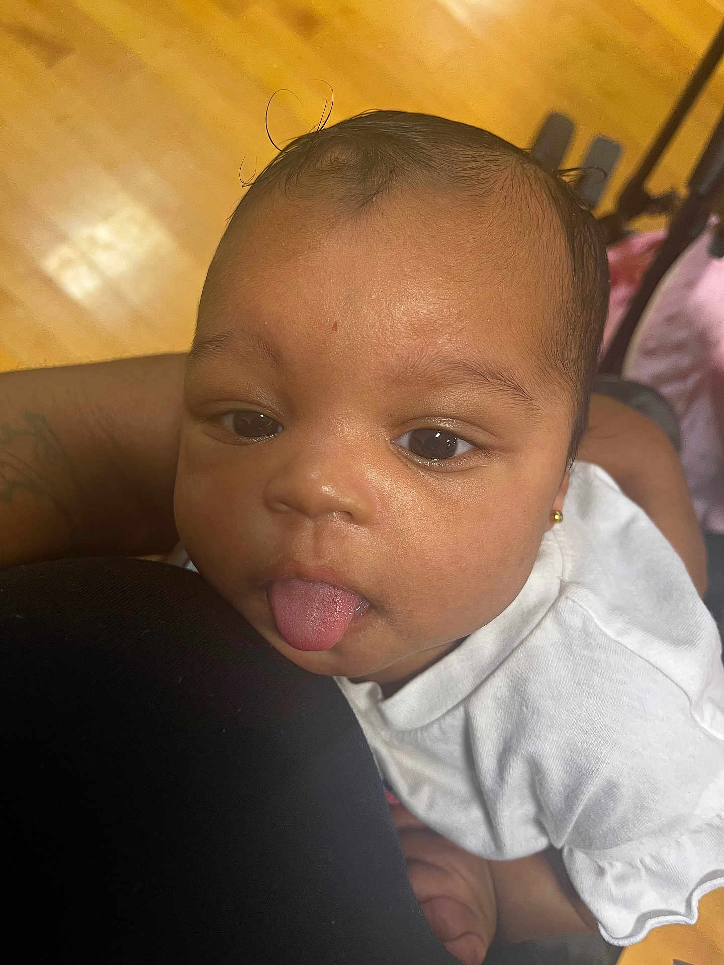 Jewel joined the competition — help win amazing prizes! baby, child, face, tongue, expression, skin, white_clothing, earrings, arm, hand, person, indoor, floor, wood, cute, resting, closeup, portrait, smiling, playful