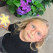 Penelope Rose is registered to the contest to win money with this photo: black_shirt, blonde_hair, casual_clothing, child, close_up, concrete_floor, cookie, cute, flower, girl, glasses, greenery, happy, holding, hydrangea, indoor, looking_up, plant_pot, portrait, sprinkles