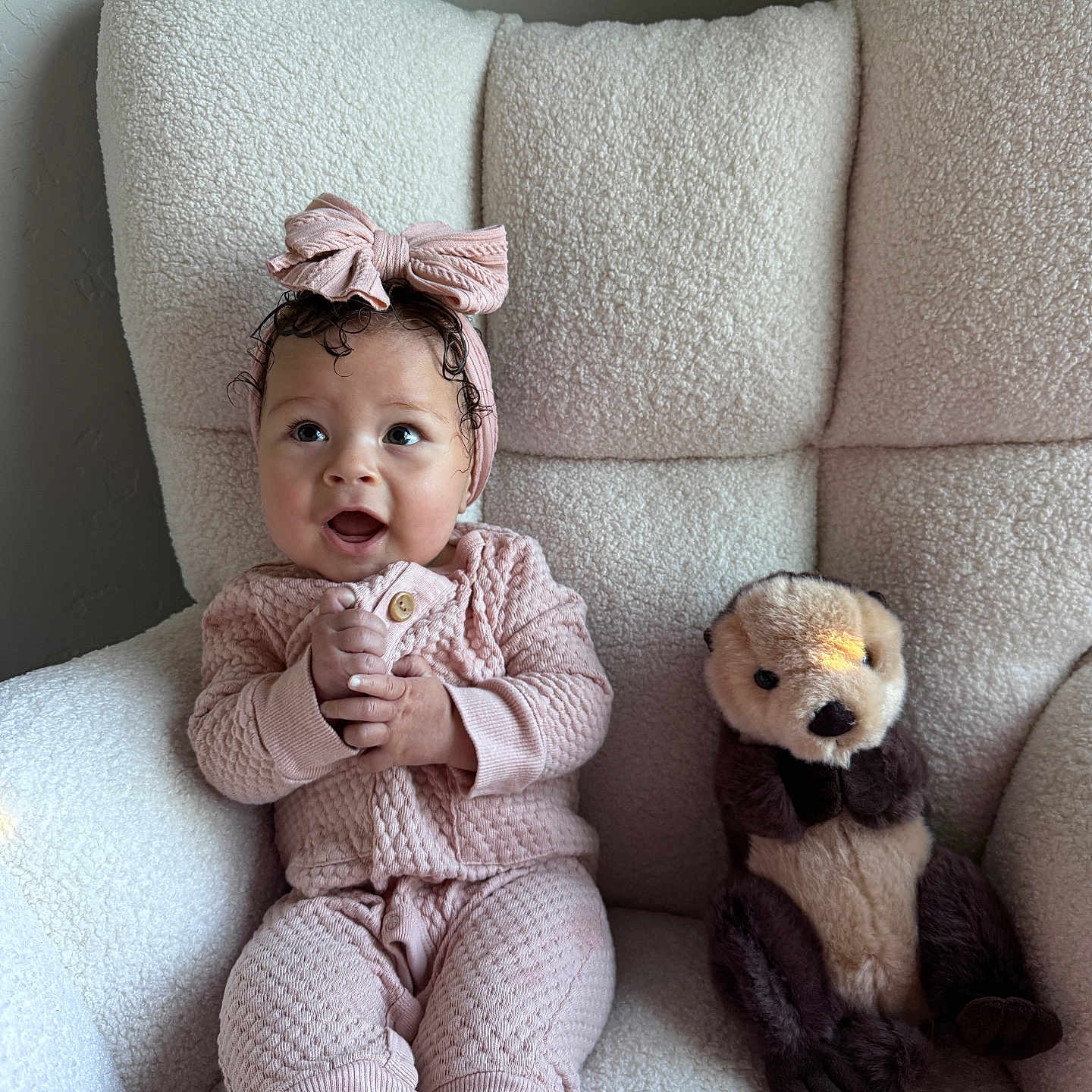 Arrow Saige is registered to the contest to win money with this photo: baby, bow, chair, child, couch, cozy, cute, furniture, happy, headband, indoors, knitwear, otter_toy, person, pink_clothing, plush_toy, seated, smiling, soft_light, toddler