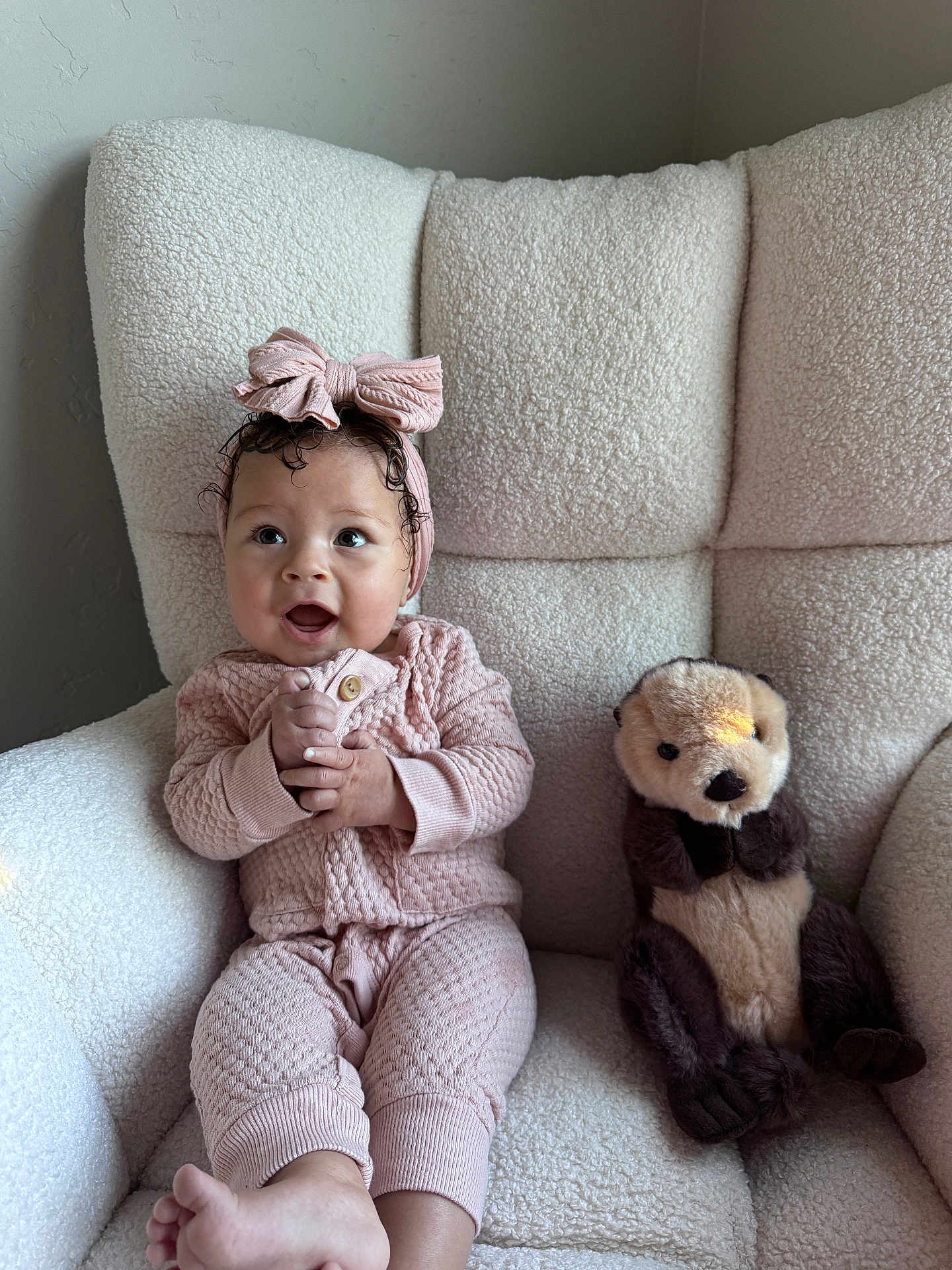 Arrow Saige is registered to the contest to win money with this photo: baby, child, pink_clothing, headband, bow, plush_toy, otter_toy, chair, cozy, knitwear, happy, smiling, indoors, soft_light, couch, toddler, cute, person, seated, furniture