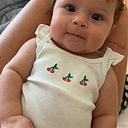 Arrow Saige is registered to the contest to win money with this photo: baby, child, infant, person, face, curly_hair, white_tank_top, cherry_embroidery, striped_pants, hand, lap, skin, indoor, blanket, soft_lighting, smile, cute, portrait, relaxed, closeup