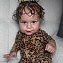 toddler, child, leopard_print, onesie, curly_hair, hair_ties, chair, white_background, portrait, indoor, soft_lighting, cute, confident, expression, person, seated, baby, fashion, looking_at_camera, cozy