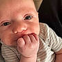 baby, close_up, face, hand, infant, onesie, striped_clothing, cute, skin, expression, newborn, person, child, portrait, young, small_hand, indoors, soft_light, human, cute_face
