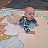 Jameson is registered to the contest to win money with this photo: awake, baby, bedroom, blanket, carpet, child, crawling, eyes, face, indoor, infant, lying_down, pants, plaid_shirt, play_mat, portrait, smiling, stars, teddy_bear, tummy_time
