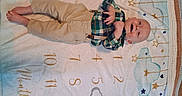 Jameson is registered to the contest to win money with this photo: baby, barefoot, blanket, child, closeup, face, happy, indoor, infant, khaki_pants, lying_down, numbered_blanket, nursery, photograph, plaid_shirt, playful, portrait, smiling, star_pattern, suspenders
