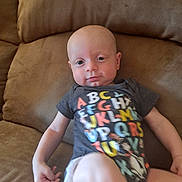 Jameson joined the competition — help win amazing prizes! baby, child, infant, couch, sofa, clothing, onesie, alphabet, colorful, furniture, indoors, person, portrait, sitting, relaxed, skin, head, face, arm, leg
