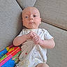 Jameson is registered to the contest to win money with this photo: baby, infant, onesie, couch, fabric, hand, face, toy, colorful, soft_book, animal_print, child, indoor, cute, young, lying_down, clothing, skin, expression, comfort