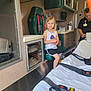 ambulance, cabinet, child, girl, green, healthcare, interior, medical, medical_equipment, paramedic, person, red, seat, shorts, smile, stretcher, tank_top, waiting, white, window