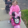 baby, casual_clothing, child, daytime, footwear, grass, happy, hoodie, outdoor, person, pink, play, residential, scooter, sidewalk, smiling, stroller, sunny, toy, vehicle