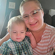 Preston is registered to the contest to win money with this photo: child, toddler, woman, glasses, plaid_shirt, striped_shirt, smiling, indoor, chair, person, portrait, family, light_switch, window, arm, hair, face, candid, comfort, casual