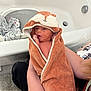 baby, newborn, towel, hooded_towel, animal_design, bathtub, bathroom, person, holding, infant, cute, wrapped, soft, carpet, laundry_basket, clothing, skin, expression, indoor, gentle