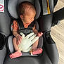 newborn, baby, car_seat, infant, sleeping, toy, inflated_glove, bandage, foot, gray, seat_belt, indoor, wood_floor, child, resting, small_hands, small_feet, head, clothing, safety