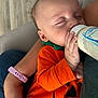arm, baby, bottle, casual_clothing, child, closeup, comfort, cute, feeding, hand, human, indoor, infant, newborn, orange_clothing, peaceful, person, portrait, resting, sleeping