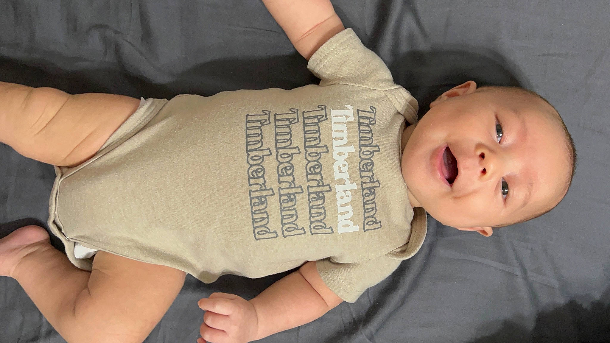 Jensen is registered to the contest to win money with this photo: arm, baby, baby_toddler_clothing, cheek, comfort, elbow, finger, gesture, hand, human, human_body, joint, knee, nail, person, sleeve, smile, thigh, toddler, tree