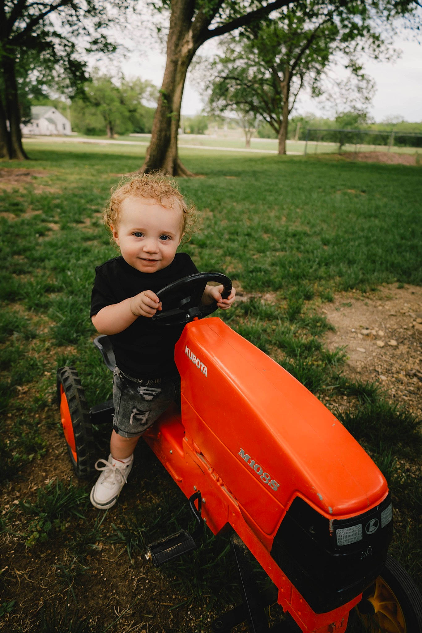 Emory joined the competition — help win amazing prizes! automotive_tire, baby, baby_toddler_clothing, grass, happy, joy, orange, people_in_nature, person, plant, riding_toy, rolling, sitting, sky, soil, tire, toddler, tractor, tree, vehicle