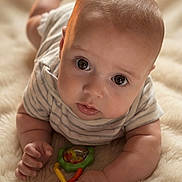 Will is registered to the contest to win money with this photo: baby, infant, toy, rattle, blanket, soft, cute, child, portrait, lying_down, curious, closeup, indoor, skin, head, eyes, hand, clothing, striped_shirt, play
