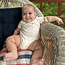 Will is registered to the contest to win money with this photo: baby, infant, wicker_chair, cushion, plaid_pattern, smiling, relaxed, outdoor, porch, wooden_railing, cute, chubby, onesie, person, skin, foot, hand, head, face, seated