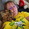 brown_dog, casual, comfort, couch, cozy, dog, flower_print, glasses, home, indoor, lemon_print, person, pet, pillow, portrait, red_heart, relaxing, snuggling, teddy_bear, yellow_shirt