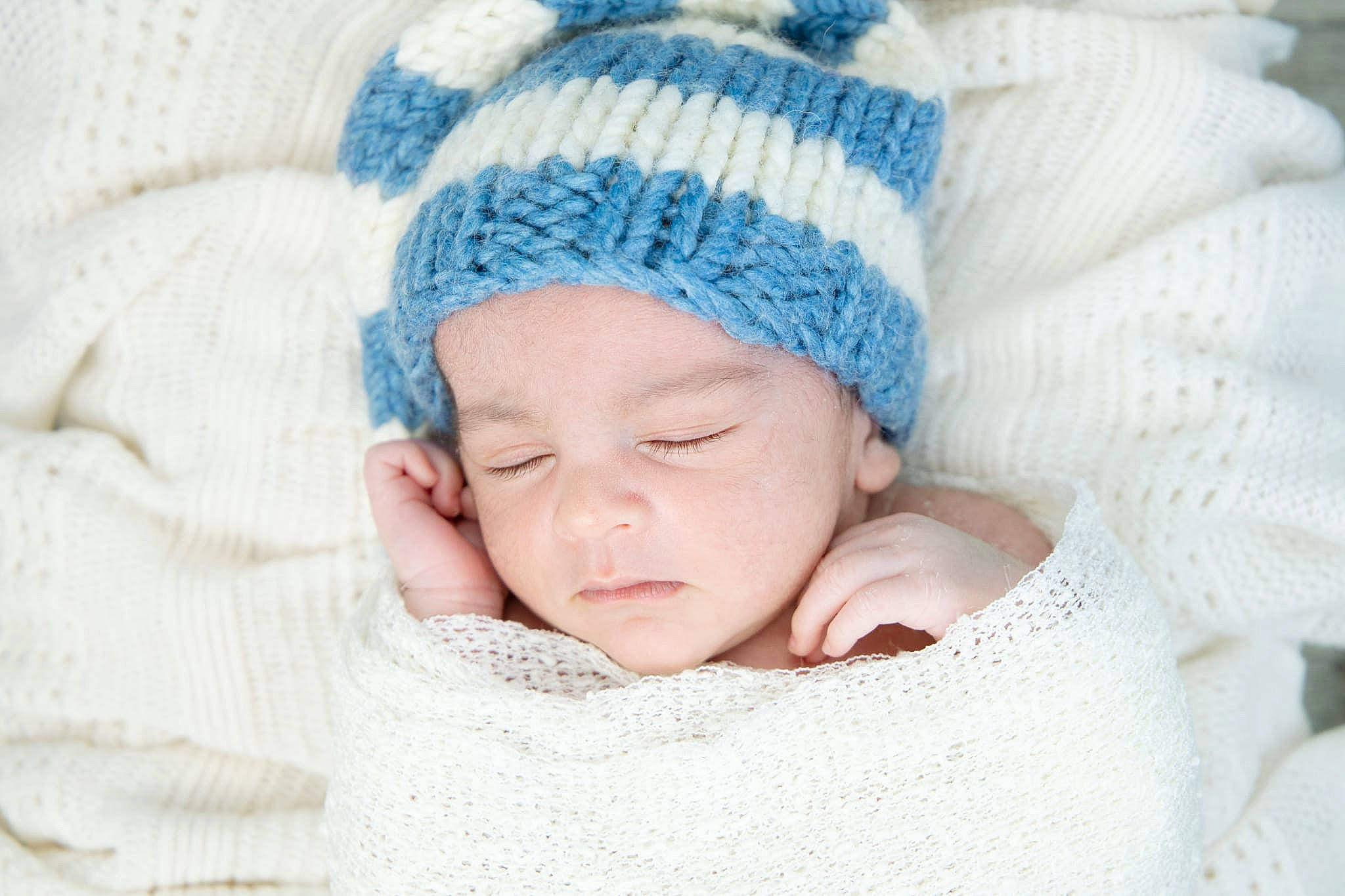 Emmanuel participe au concours pour gagner de l'argent avec cette photo : baby, baby_products, baby_sleeping, baby_toddler_clothing, beanie, bedtime, cap, cheek, comfort, face, fashion_accessory, hand, headgear, headwear, knit_cap, linens, person, sleeve, textile, toddler