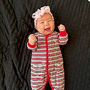 Aryana joined the competition — help win amazing prizes! baby, infant, smiling, striped_clothing, onesie, headband, pink_bow, teddy_bear_patch, black_blanket, happy, fists_raised, lying_down, cute, child, portrait, indoors, cheerful, baby_girl, expression, soft_lighting