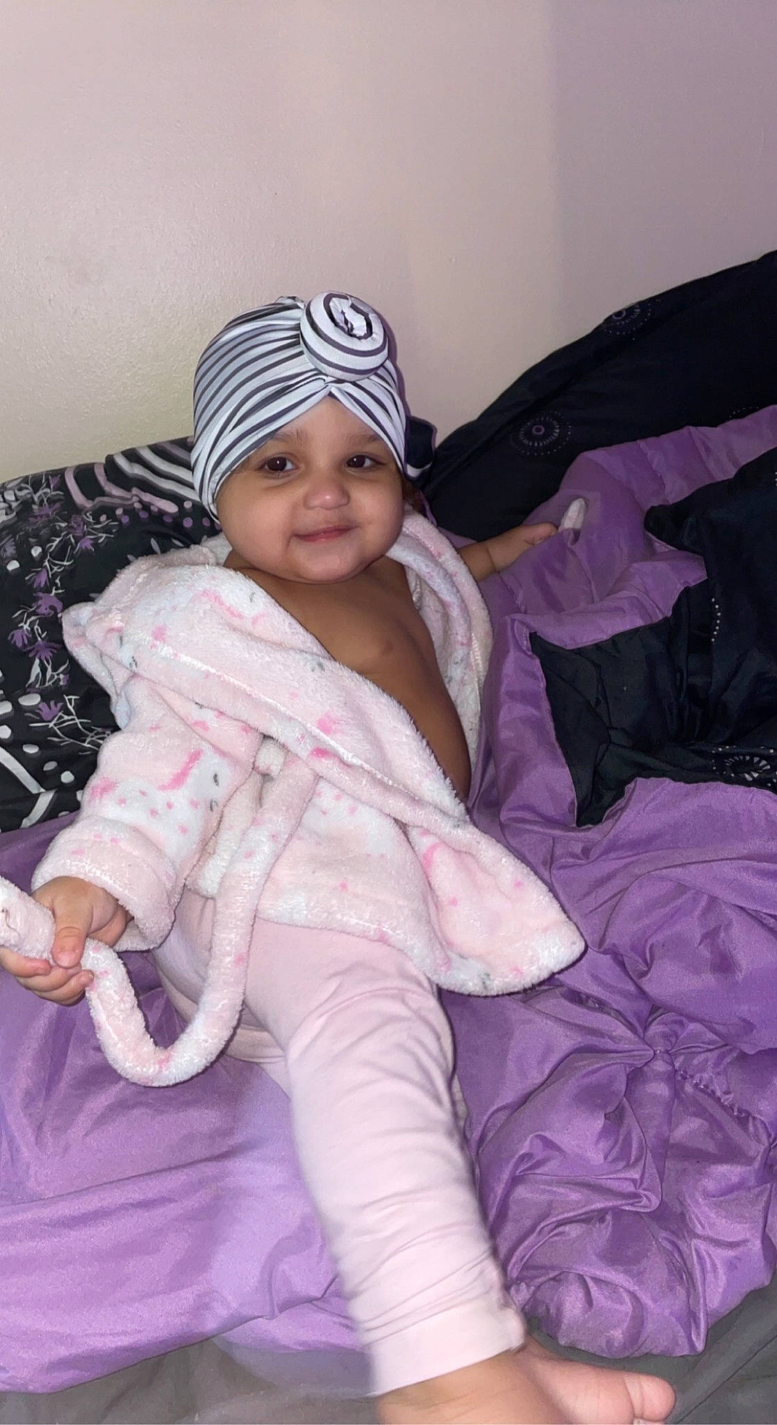 Bianca is registered to the contest to win money with this photo: baby, baby_toddler_clothing, cap, cheek, child, comfort, fun, happy, headwear, joy, linens, magenta, mammal, outerwear, person, pink, purple, sitting, skin, smile