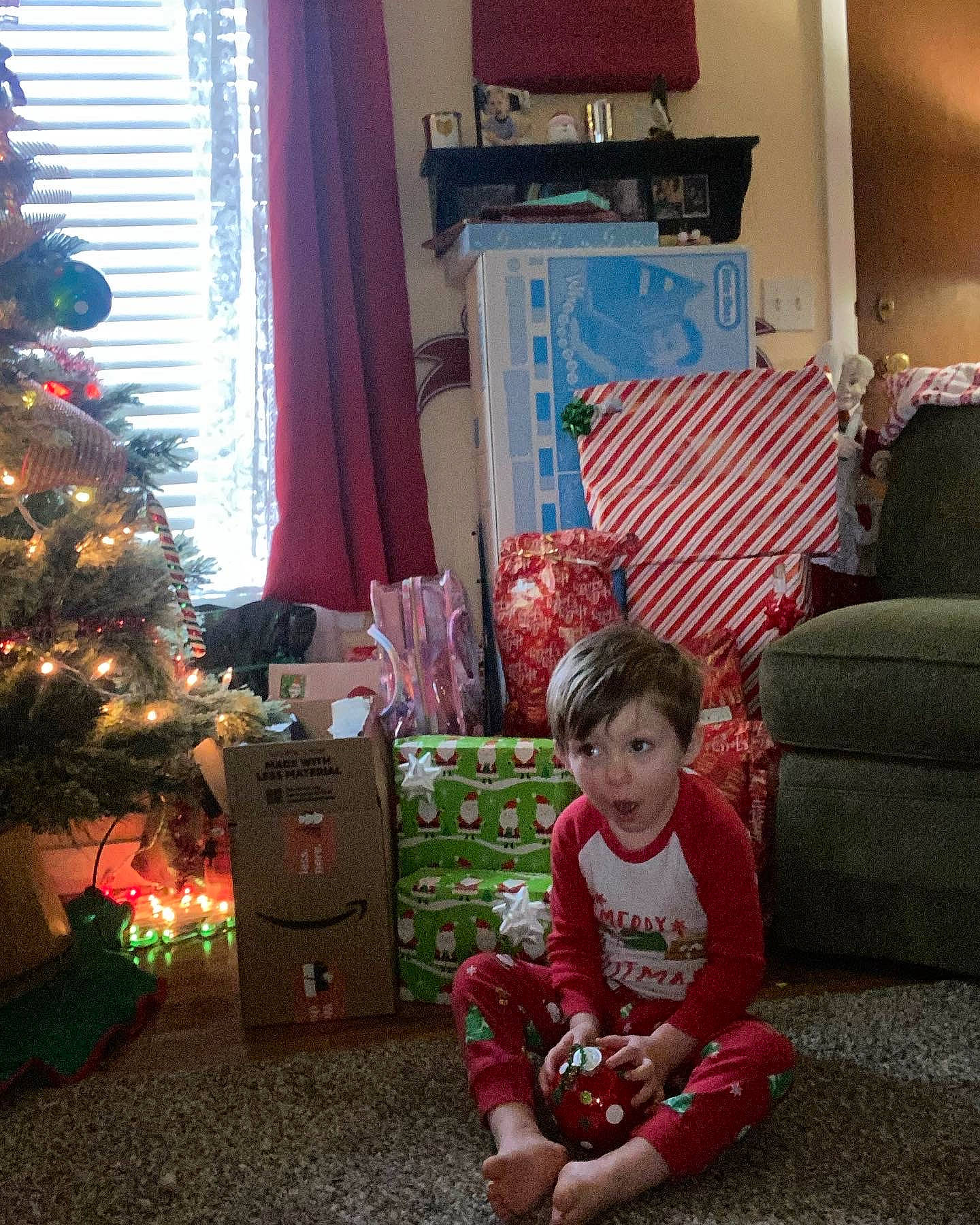 Uriah Dean is registered to the contest to win money with this photo: baby_toddler_clothing, beauty, christmas, christmas_decoration, christmas_ornament, christmas_tree, green, holiday, interior_design, lap, living_room, ornament, person, photograph, plant, red, surprise, toddler, tree, window