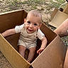 baby, child, cardboard_box, outdoor, grass, dirt, smiling, sitting, cute, playful, person, head, face, short_sleeves, barefoot, sunlight, natural_light, ground, box_flaps, happy