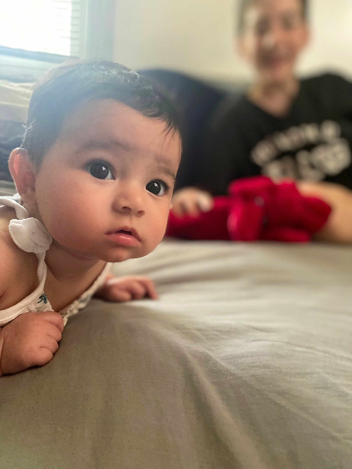 Elliana is registered to the contest to win money with this photo: baby, child, bed, indoor, person, face, curious, young, smile, blurred_background, window, soft_light, skin, hair, clothing, hand, looking, lying_down, portrait, home