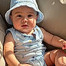 baby, child, infant, hat, bucket_hat, blue_clothing, sleeveless, sunlight, cushion, beige, skin, face, hand, leg, cute, portrait, indoors, person, relaxed, seated