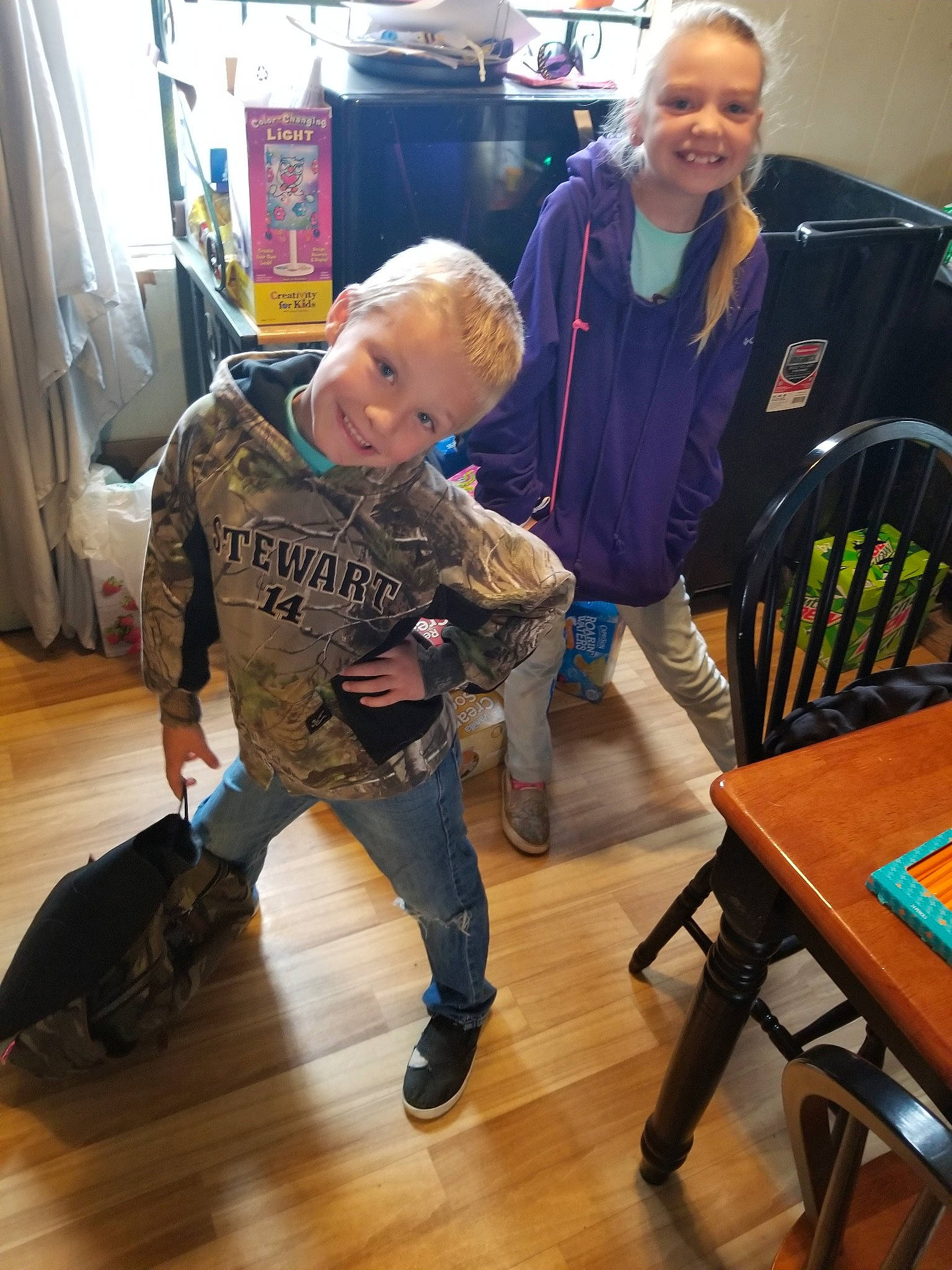 Kylor is registered to the contest to win money with this photo: backpack, bag, boot, chair, child, curtain, denim, event, floor, flooring, fun, hardwood, joy, laminate_flooring, leisure, luggage_and_bags, person, room, smile, table