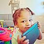 toddler, child, tablet, braided_hair, indoor, play_area, toy, couch, smile, face, person, young_child, furniture, plastic_toy, colorful, happy, portrait, hand, living_room, curly_hair